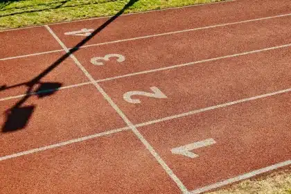Atletas compitiendo en una pista de atletismo bajo luces de estadio