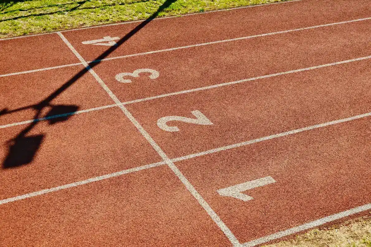 Atletas compitiendo en una pista de atletismo bajo luces de estadio