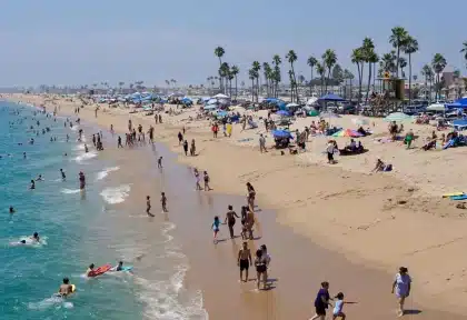 Playa abarrotada con sombrillas de colores, toallas y familias descansando en la arena tras la reapertura.