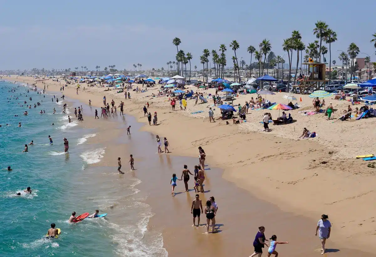 Playa abarrotada con sombrillas de colores, toallas y familias descansando en la arena tras la reapertura.