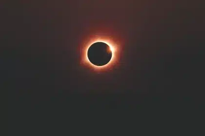 Silueta de un observador mirando hacia el cielo durante un eclipse solar con ciudad al fondo en sombra