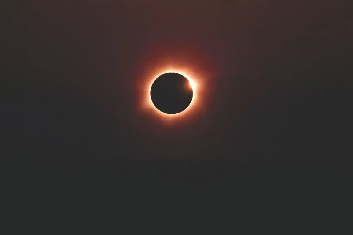 Silueta de un observador mirando hacia el cielo durante un eclipse solar con ciudad al fondo en sombra