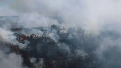 Vista aérea de terreno incendiado con humo y helicópteros de extinción sobrevolando el bosque