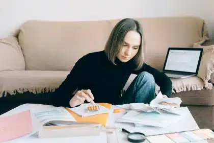 Facturas y recibos sobre una mesa con calculadora y café, simbolizando la presión presupuestaria