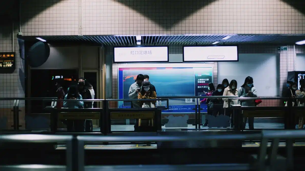Pasajeros esperando en un andén de estación de tren durante hora punta con servicio reducido