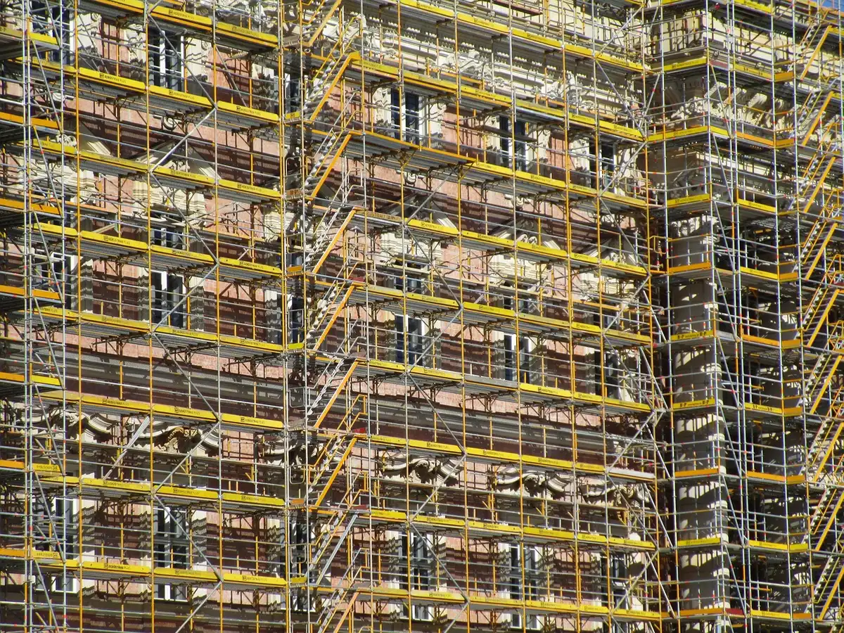 Obras de construcción de viviendas con andamios y grúas en un barrio