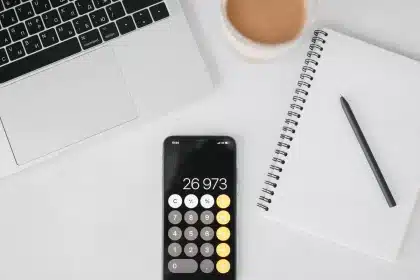 Manos anónimas revisando papeles y calculadora en mesa de oficina