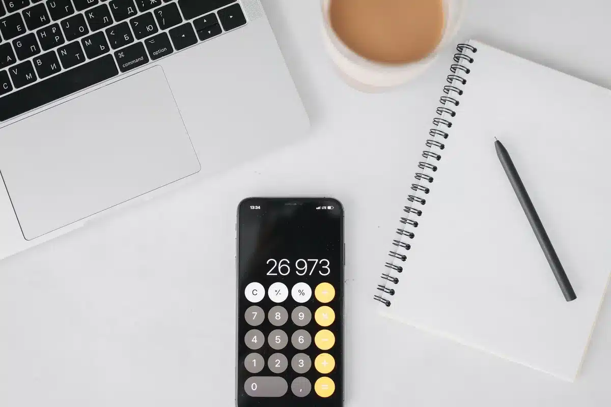 Manos anónimas revisando papeles y calculadora en mesa de oficina