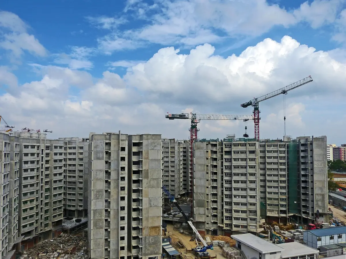 Vista aérea de desarrollo urbanístico con grúas de construcción y edificios en construcción en terrenos vacíos
