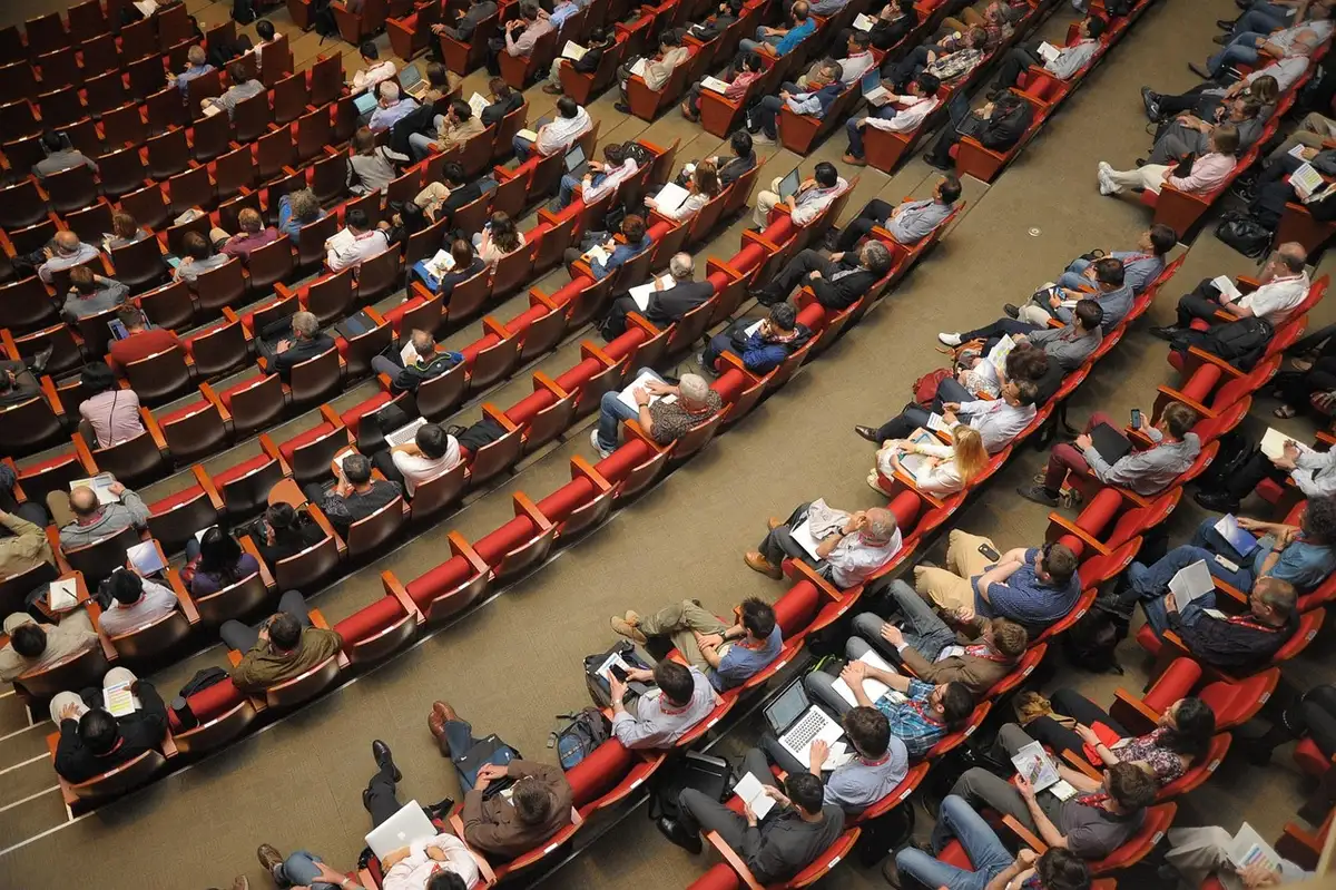 Manos y siluetas en discusión política en un salón institucional