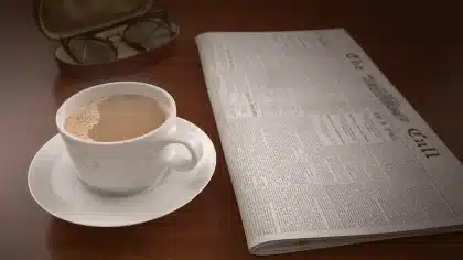 Manos sosteniendo un gráfico ascendente sobre una mesa con facturas y café desenfocados
