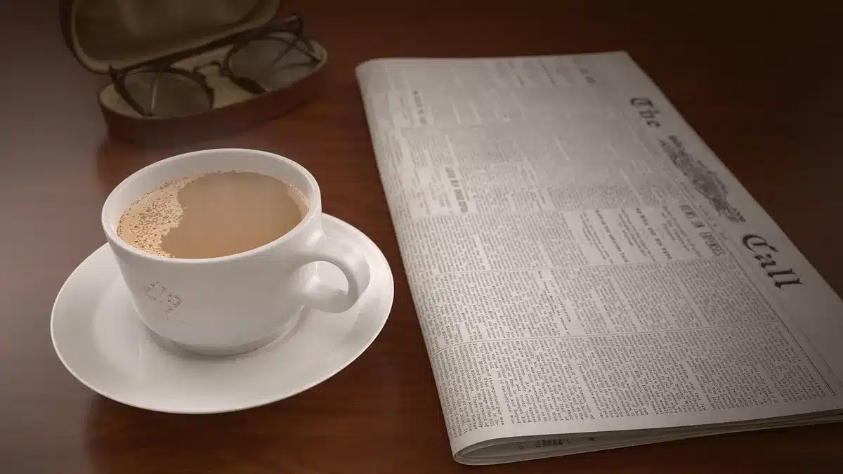 Manos sosteniendo un gráfico ascendente sobre una mesa con facturas y café desenfocados