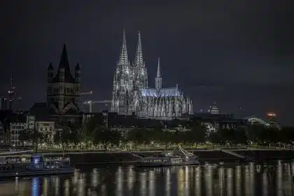 Interior de catedral con fieles en duelo sentados en bancos, velas encendidas y luz natural