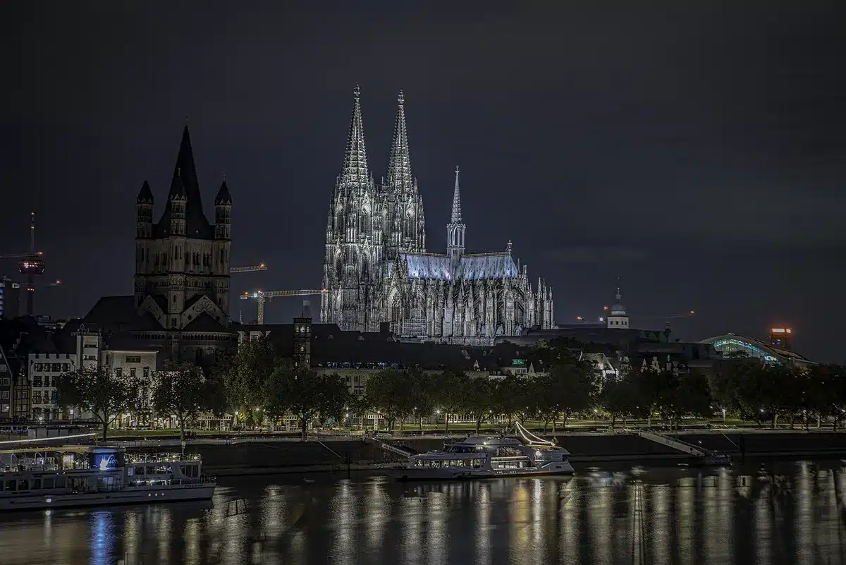 Interior de catedral con fieles en duelo sentados en bancos, velas encendidas y luz natural