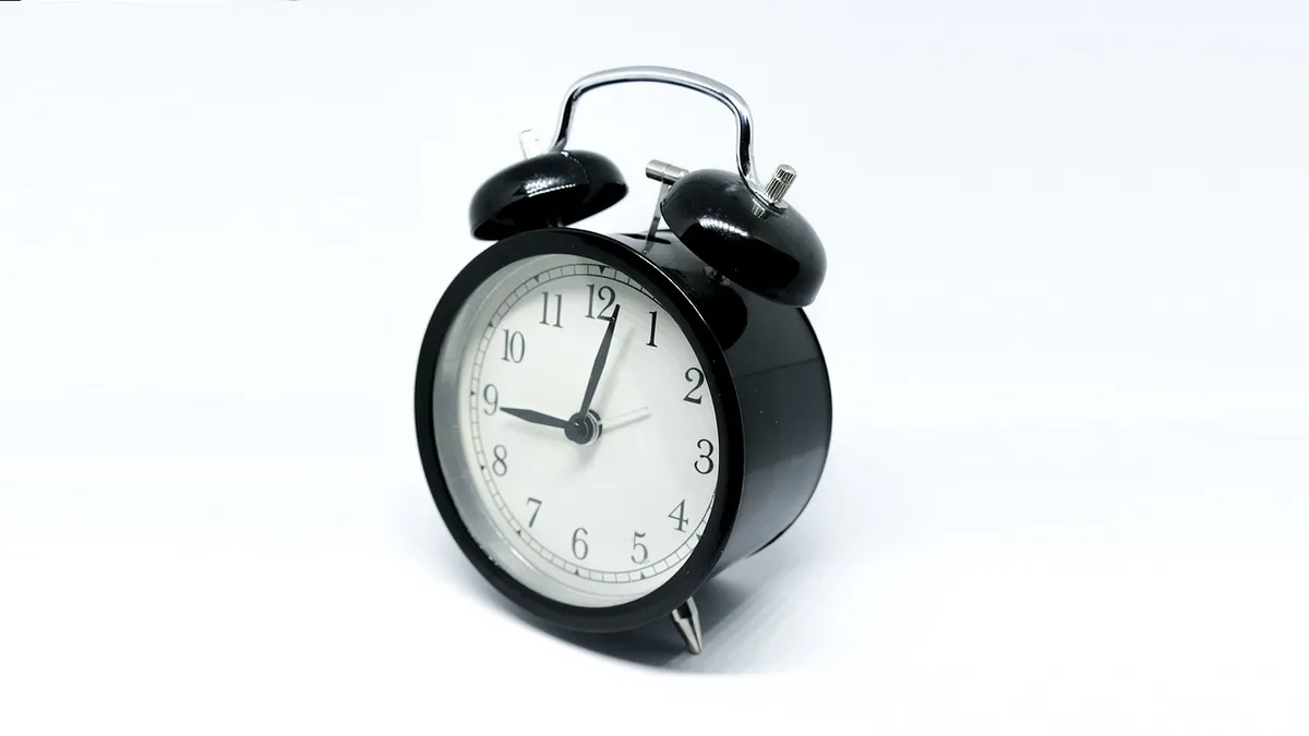 Editor frente a la pantalla con reloj y montones de papel, simbolizando retrasos