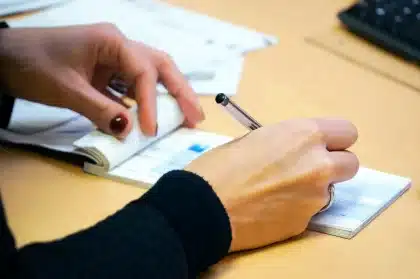 Manos anónimas con expedientes y sobres sobre una mesa de despacho