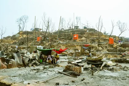 Campamento improvisado junto a edificios dañados, personas anónimas buscan refugio
