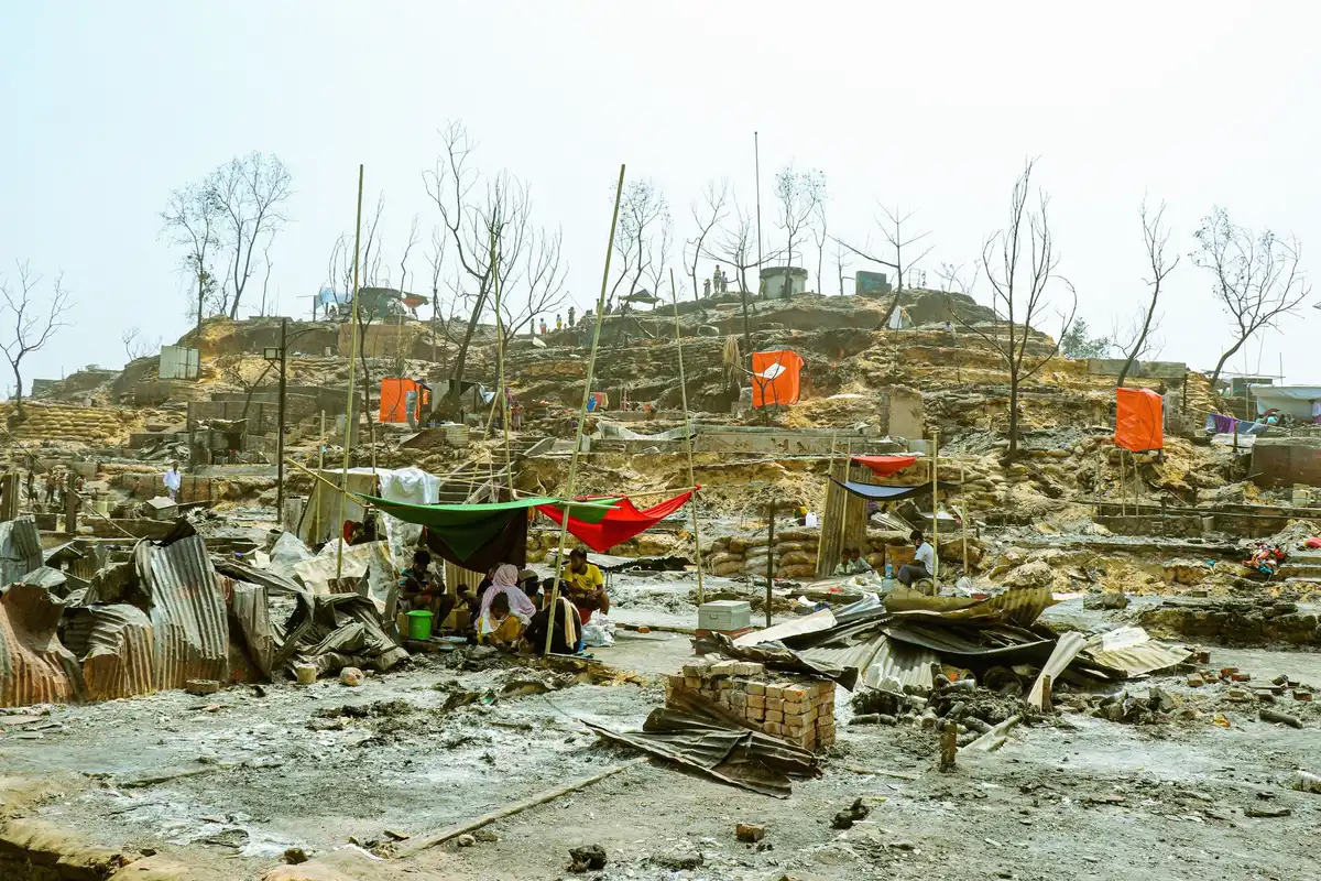 Campamento improvisado junto a edificios dañados, personas anónimas buscan refugio