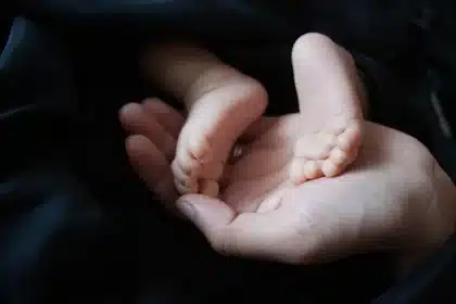 Manos de padres junto a una silla de ruedas vacía en un pasillo de centro de salud
