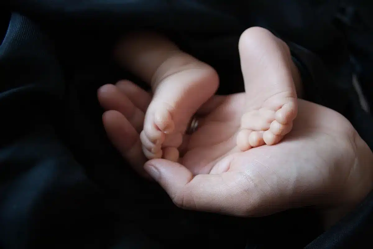 Manos de padres junto a una silla de ruedas vacía en un pasillo de centro de salud