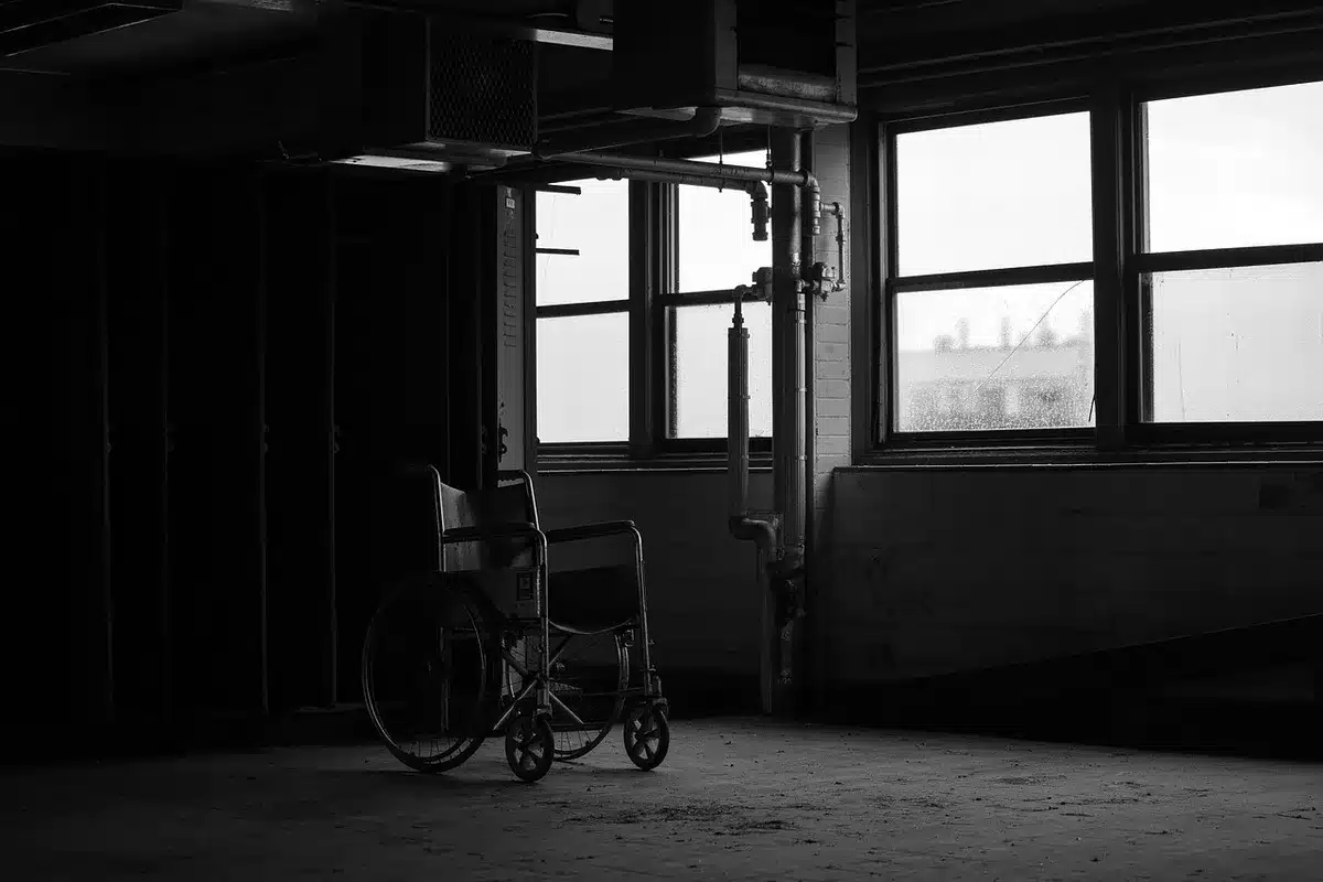 Pasillo de hospital vacío con equipo y una silla de ruedas, simbolizando la presión sobre servicios