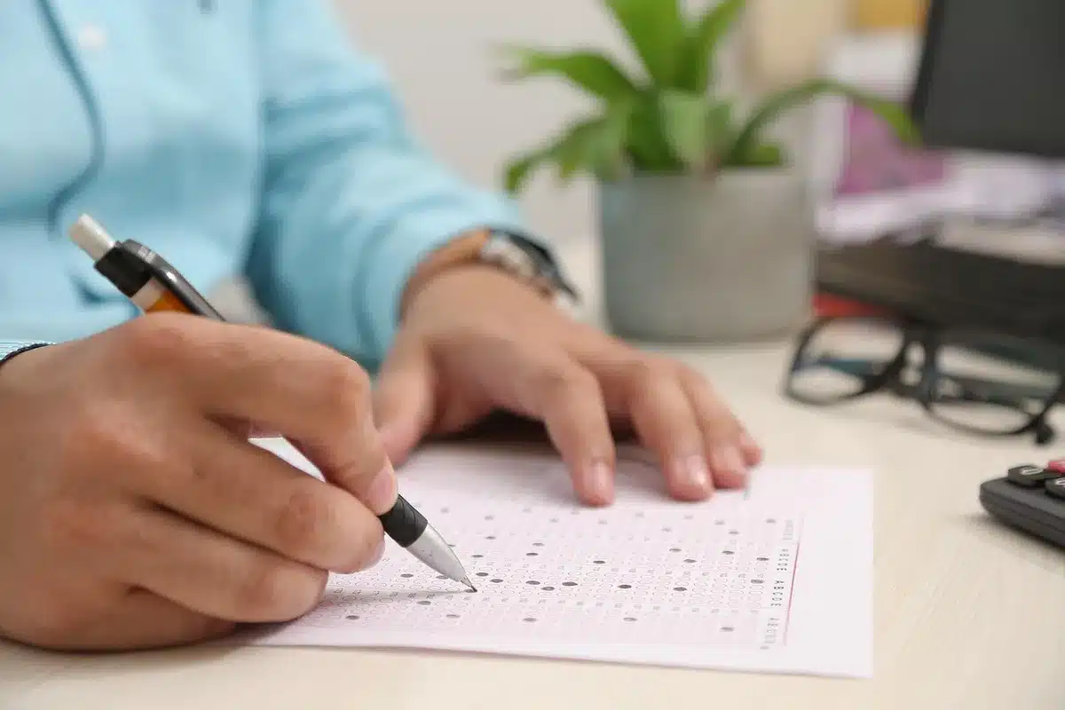 Persona rellenando un escrito de alegación en un escritorio con papeles