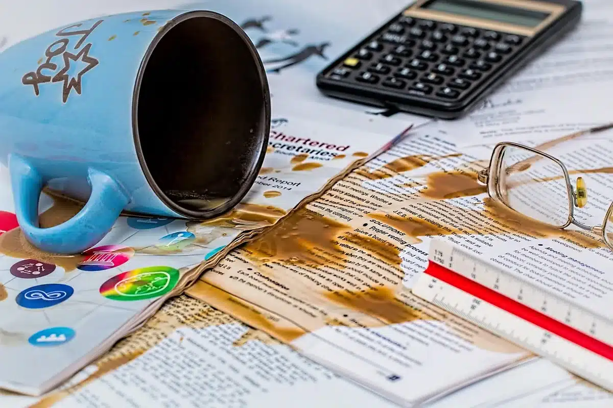 Persona anónima junto a papeles de trabajo y gesto de frustración