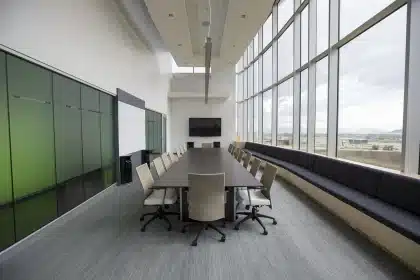 Mesa de junta con manos en silueta y silla vacía que evocan cambio de control